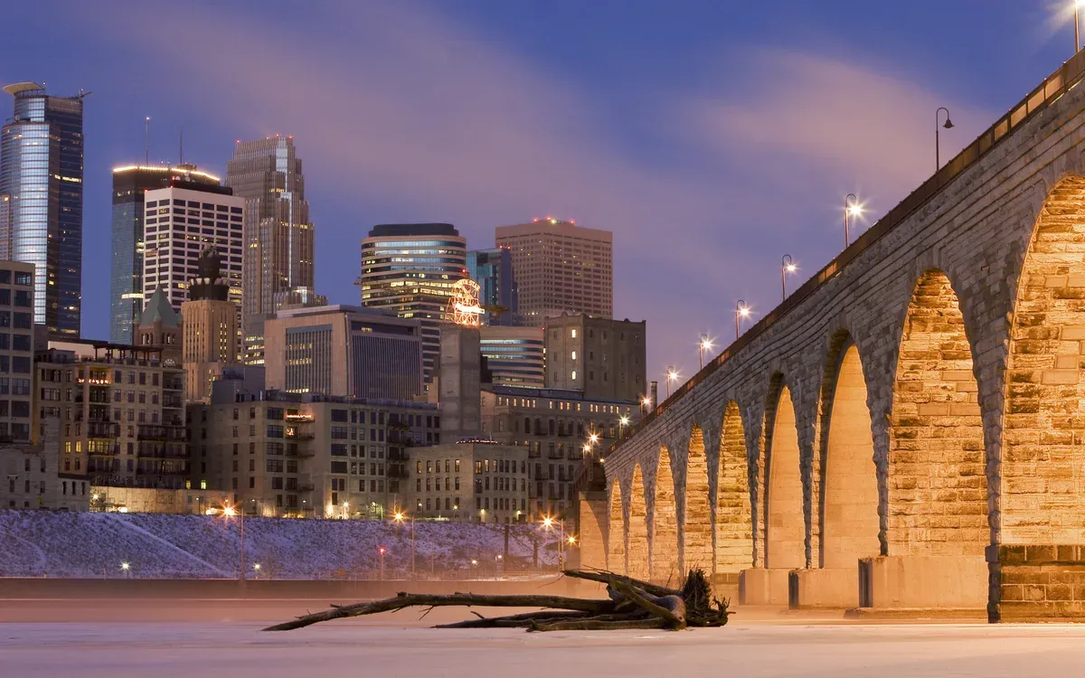 The Stone Arch Bridge leading to the downtown Minneapolis skyline at dusk