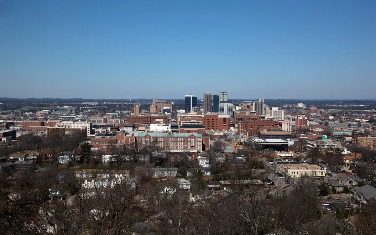 An elevated daytime view of downtown Birmingham, Alabama's skyline, with surrounding neighborhoods and bare winter trees in the foreground