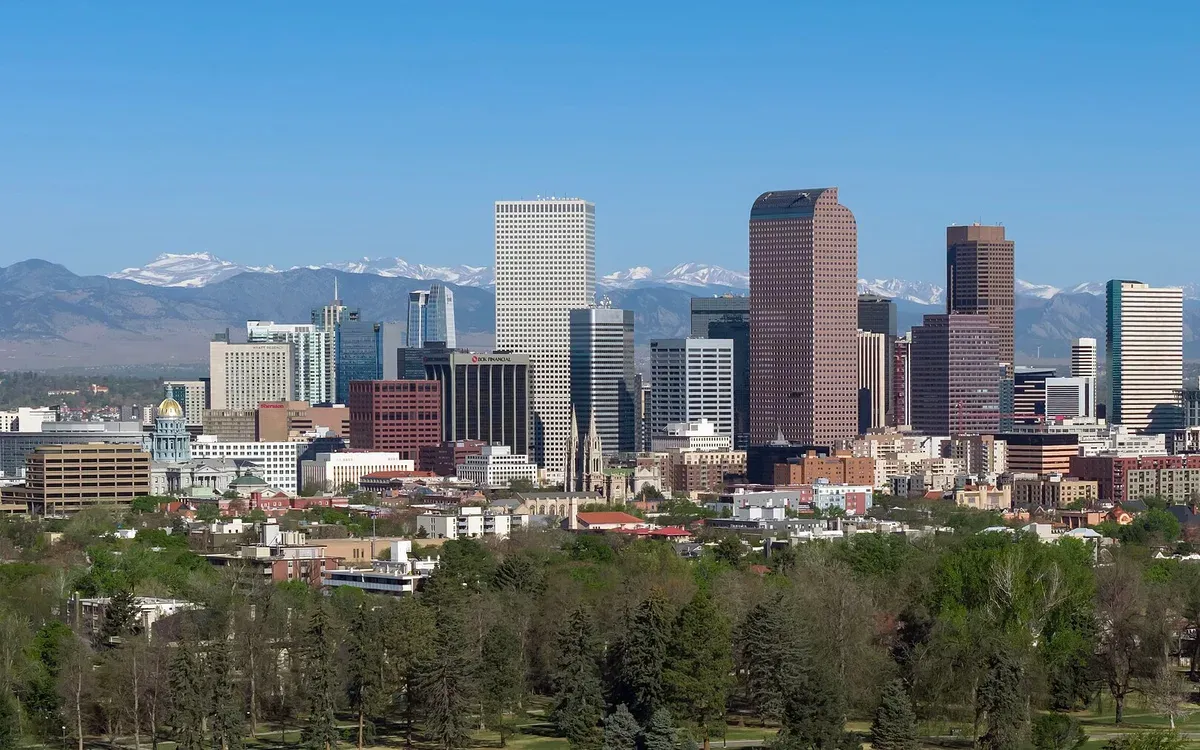 The downtown Denver, Colorado skyline on a clear day, high-rises catching the sun with the Front Range in the distance