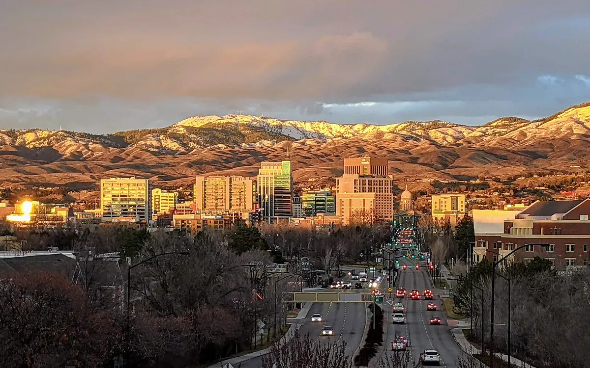 The Boise, Idaho skyline and Boise Foothills glowing under a winter sunset, with downtown traffic in the foreground