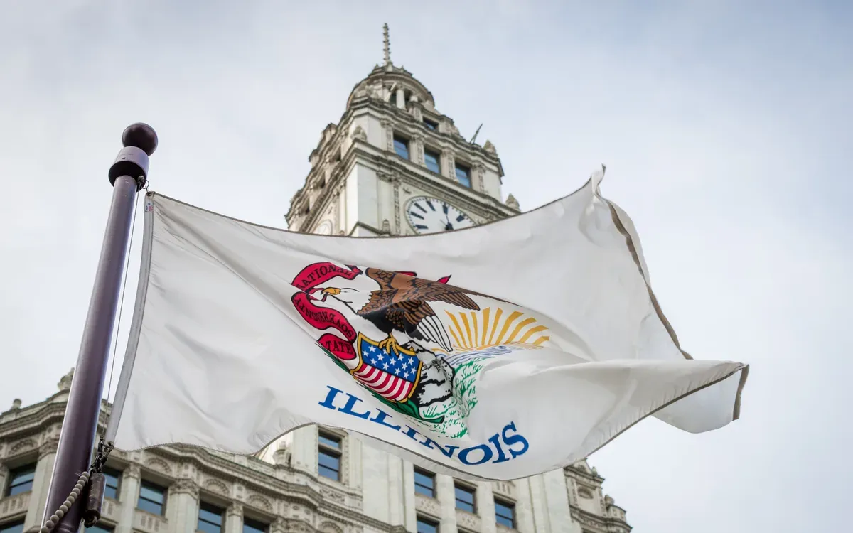 The Illinois state flag flying in downtown Chicago with the Wrigley Building clock tower behind