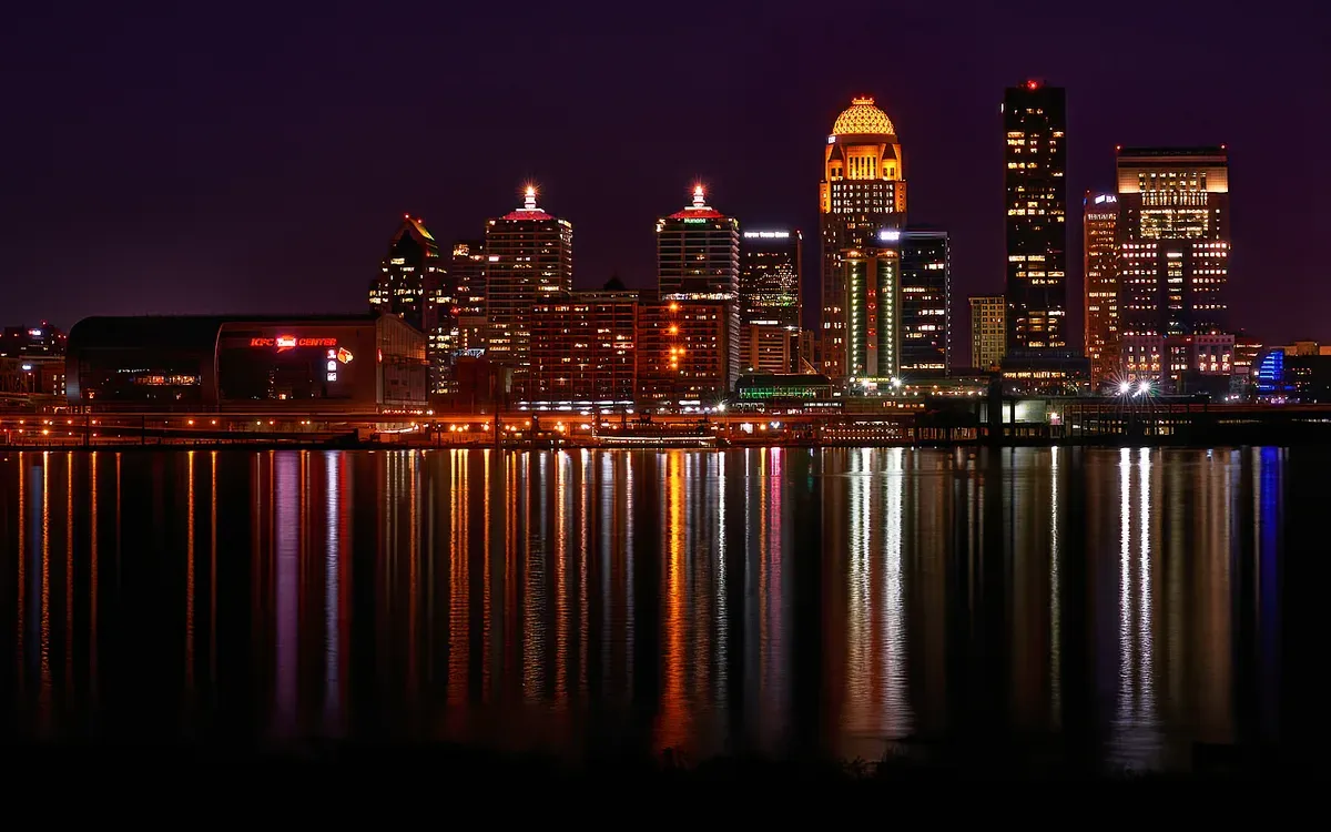 The downtown Louisville, Kentucky skyline lit up at night, reflected in the Ohio River