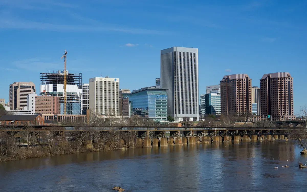 The downtown Richmond, Virginia skyline across the James River, with a rail bridge in the foreground, on a clear day