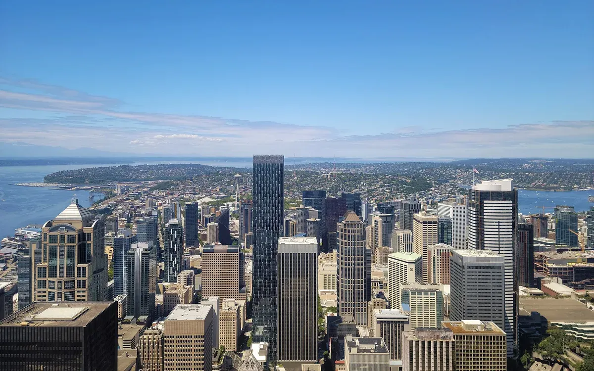 The Seattle skyline looking north from the Columbia Center observation deck, with the Space Needle, downtown towers, and Puget Sound in view